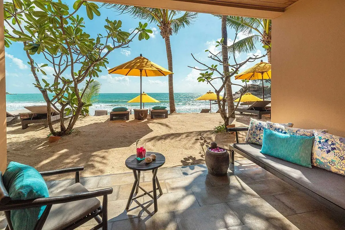Beachfront resort terrace with sun loungers and yellow umbrellas looking onto a turquoise sea, Koh Phangan, Thailand